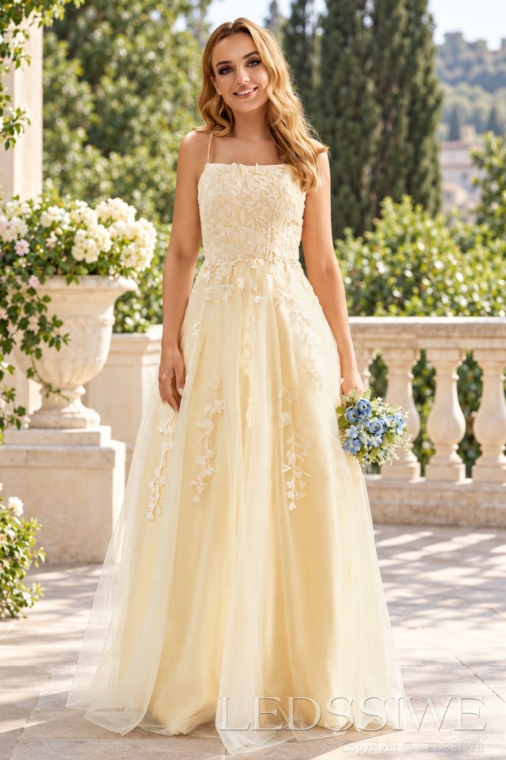 Daffodil tulle a-line prom dress with lace appliqués and lace-up back front view with bouquet