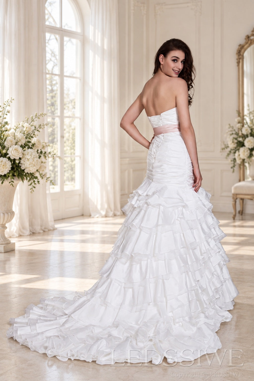 ivory strapless ruched mermaid wedding dress with tiered tulle skirt and waist bow back view